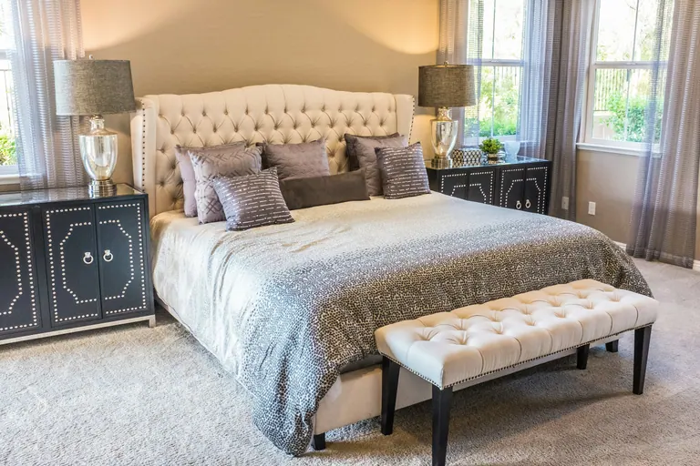 A neatly made bed in a bright finished bedroom.